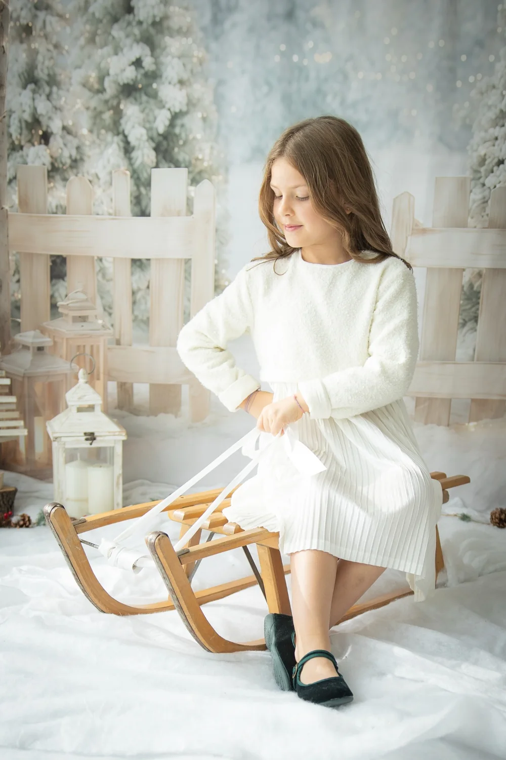 Bambina con slitta di legno sul set natalizio bianco di Click & Dreen a Pieve di Curtarolo.